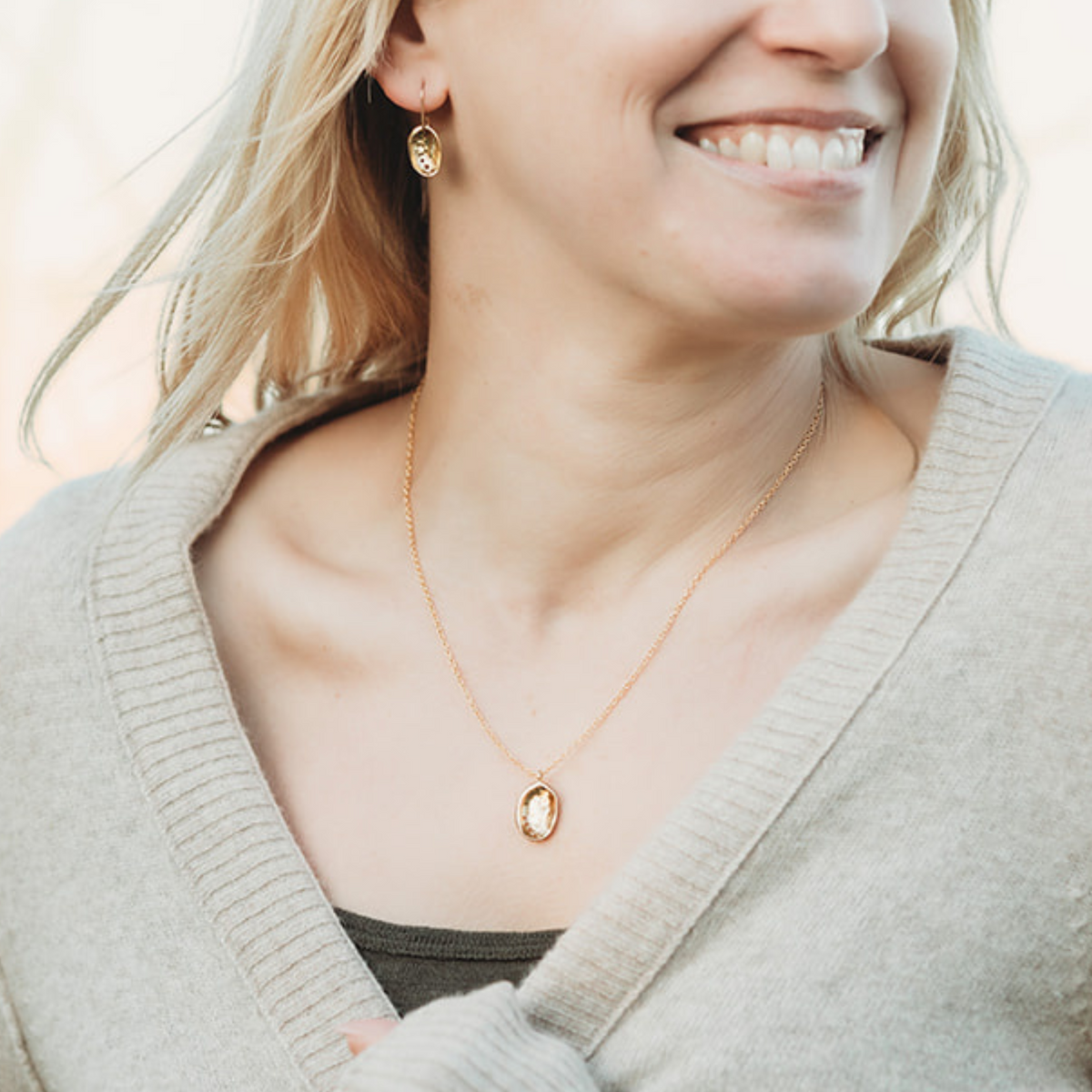 Baby Pāua Pendant Gold worn on model with matching earrings