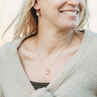 Baby Pāua Pendant Gold worn on model with matching earrings