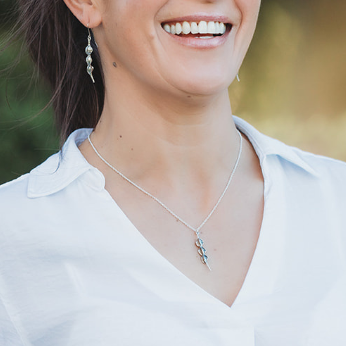 Silver Kōwhai Pod Pendant Necklace and matching Earrings worn on model