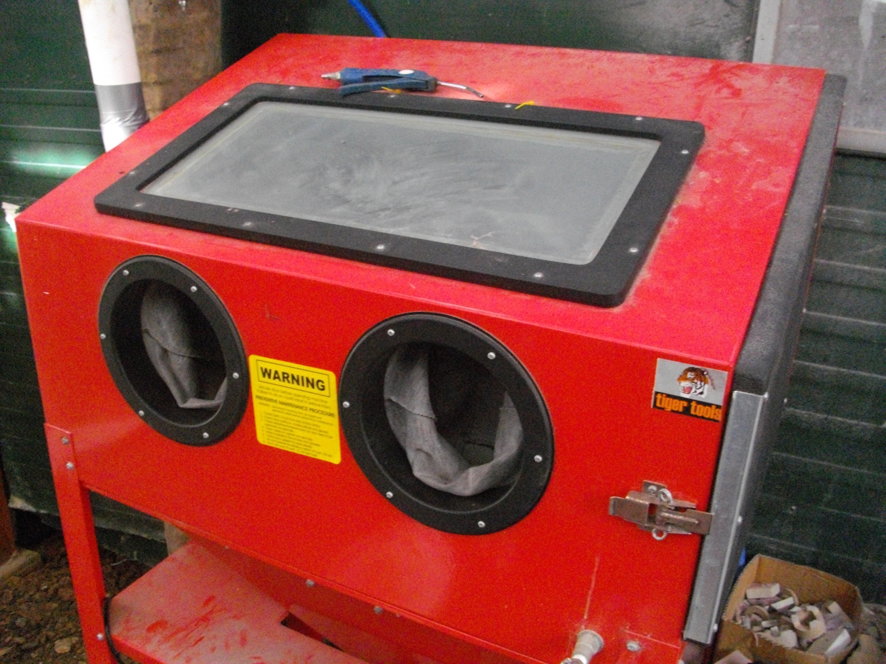 The sandblasting cabinet where we etch away only the area not masked by the sticker.